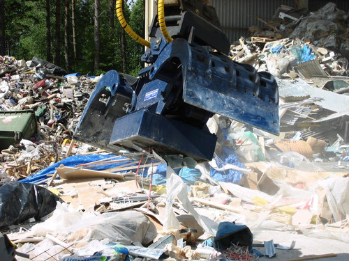 demolition grapple with scrap magnet cleaning up a waste site