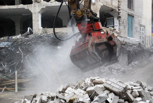 Dynaset Dust Suppression System spraying from a grapple at a demolition site