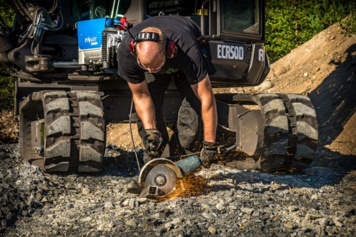 man using power grinder on steel pipe that is powered by small hydraulic generator