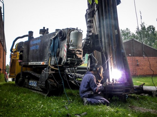 Man welding a drilling machine with a welder generator and welder stick