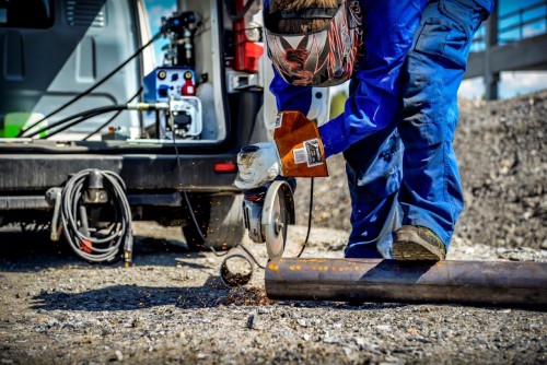 Man cutting steel pipe with circular saw powered by welder generator