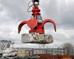 red scrap grapple with magnet moving scrap metal
