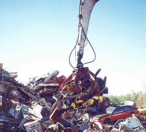 red hydraulic five tine grapple moving scrap metal