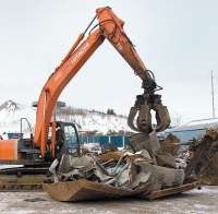 red hydraulic five tine grapple moving scrap metal